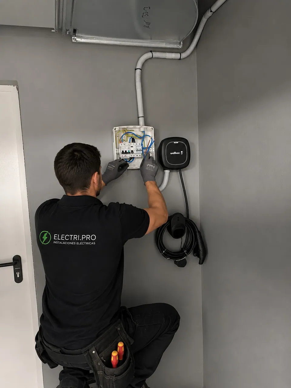 Electricista cableando la caja de protecciones de superficie junto al cargador ya montado