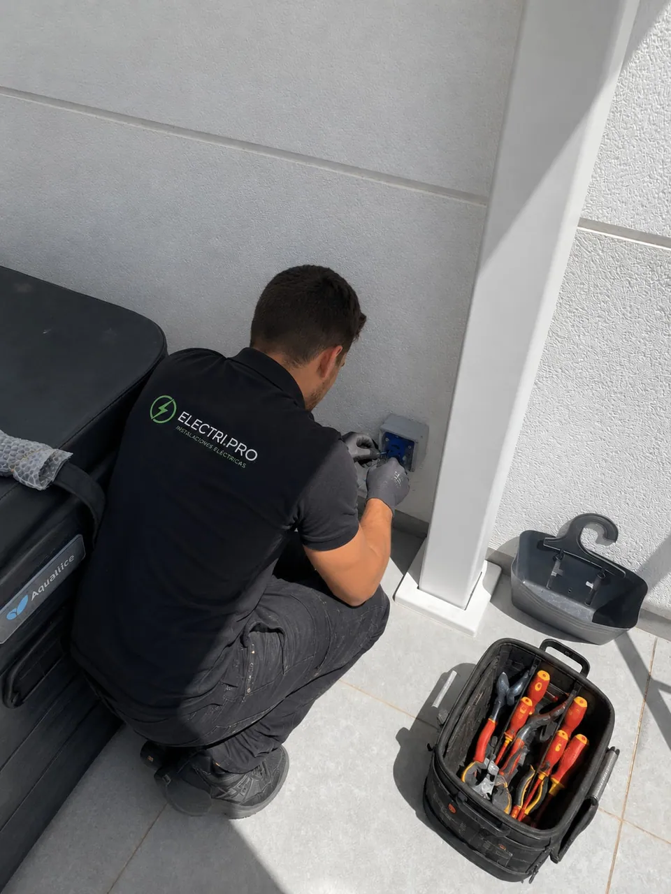 Electricista conectando una caja estanca en la pared, junto a la cubierta del spa